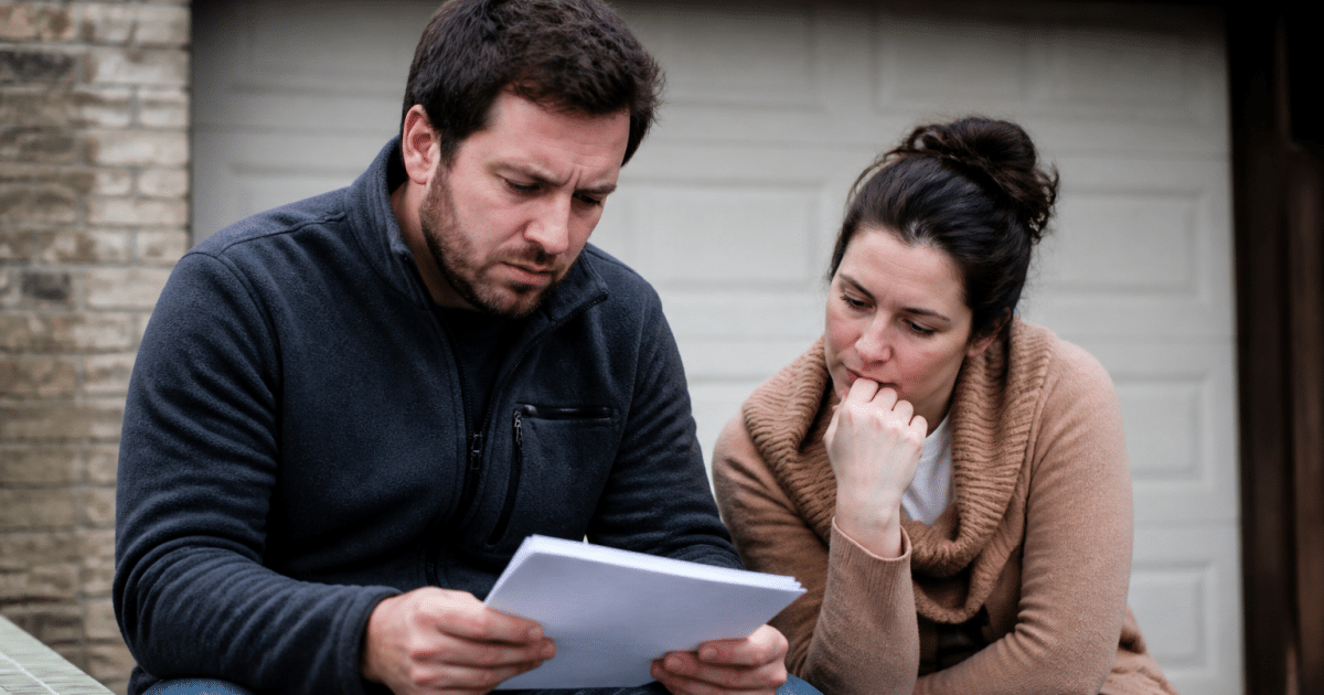 Couple examinant documents assis devant garage