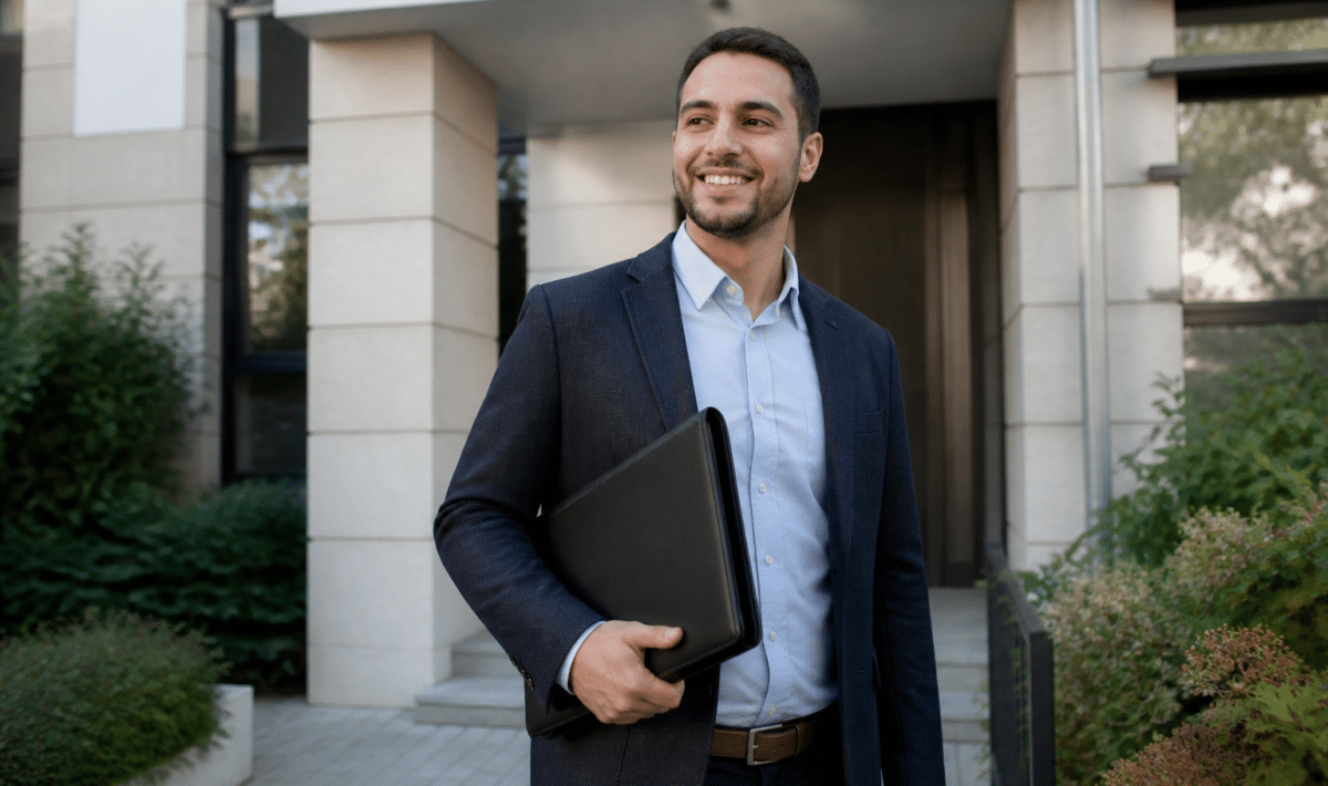 Agent immobilier souriant tenant dossier devant immeuble