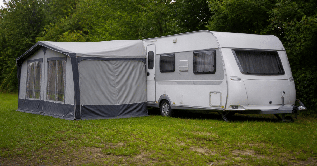 Caravane stationnée sur terrain herbeux avec annexe attachée