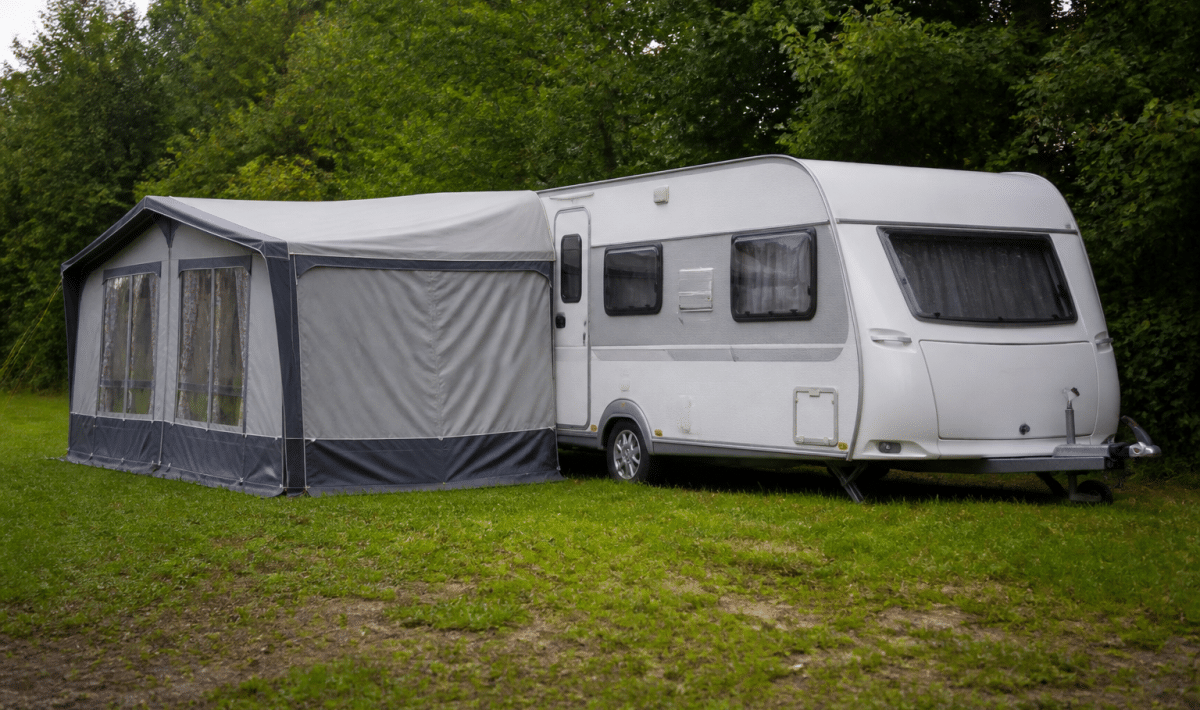 Caravane stationnée sur terrain herbeux avec annexe attachée