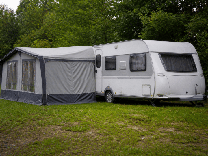 Caravane stationnée sur terrain herbeux avec annexe attachée