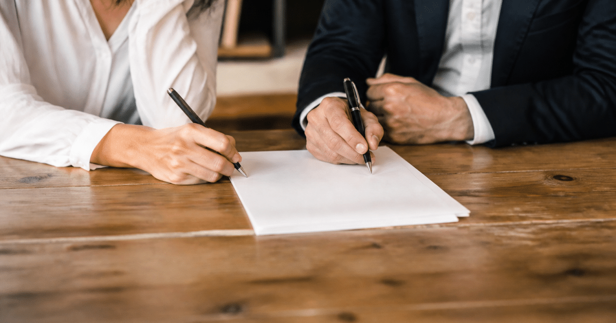 Deux personnes signant document papier sur table bois