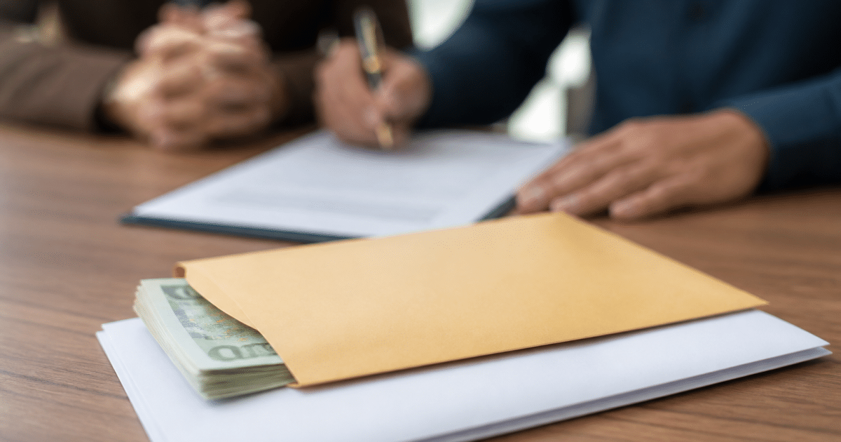 Contrat immobilier signe avec enveloppe argent liquide posee dessus