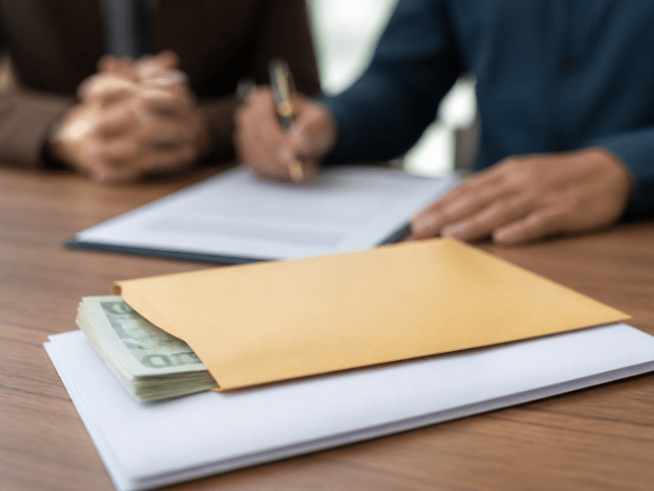 Contrat immobilier signe avec enveloppe argent liquide posee dessus