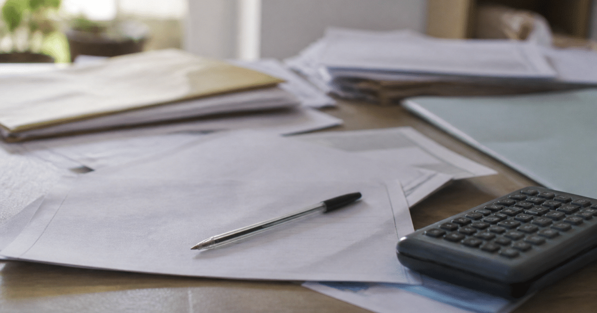 Documents administratifs etales sur bureau avec stylo et calculatrice