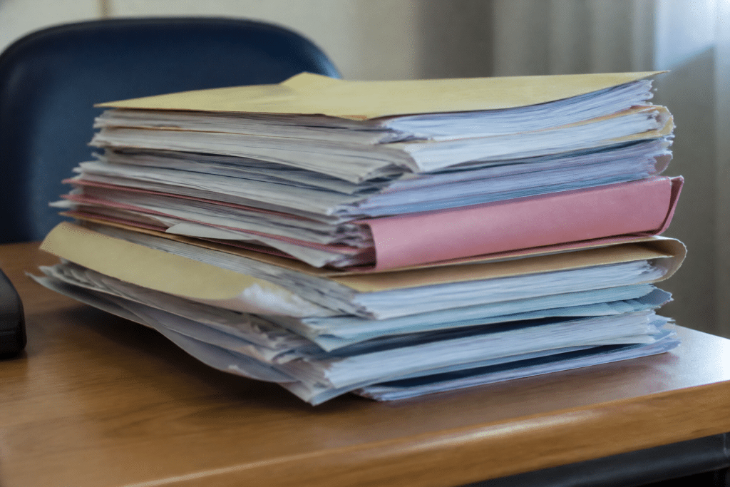Dossiers papier avec documents immobiliers et rapports medicaux empiles.