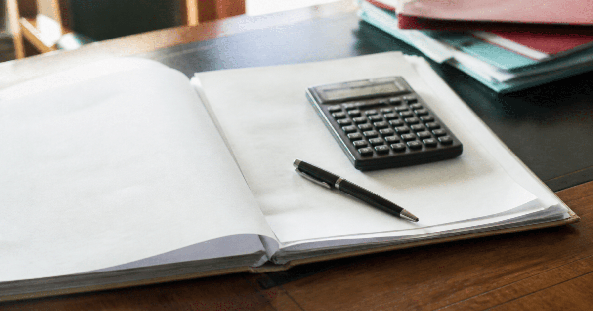 Document notarial ouvert sur bureau avec calculatrice et stylo poses dessus