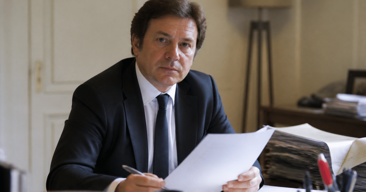 Notaire assis a son bureau tenant document officiel signe