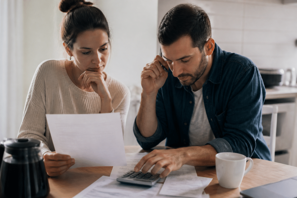 Deux personnes examinent documents pret immobilier avec calculatrice