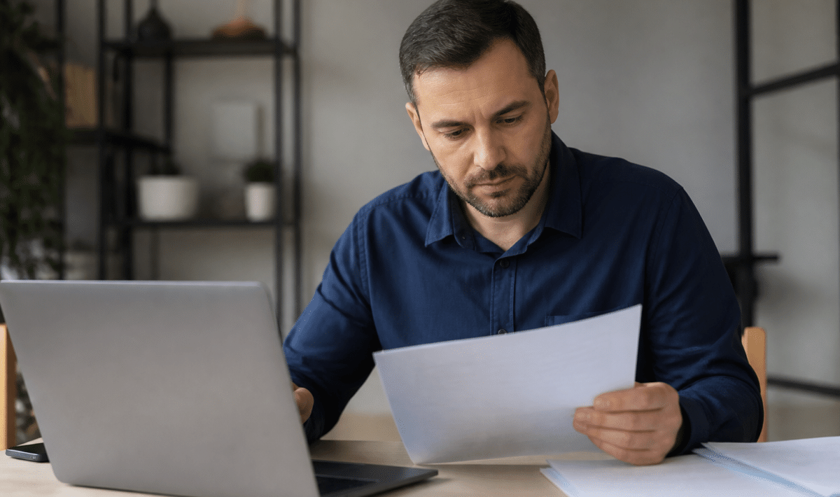 Homme consultant document financier pres ordinateur bureau