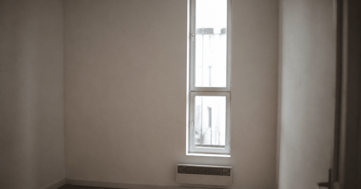 Petit studio vide avec murs blancs et fenetre etroite