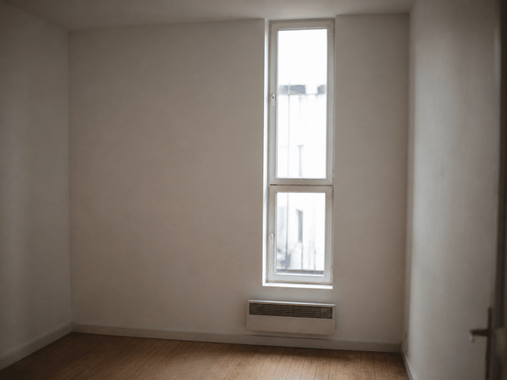 Petit studio vide avec murs blancs et fenetre etroite